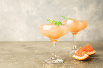 Drink grapefruit rosemary and ice two elegant glass goblets on gray concrete background. A refreshing summer cocktail.