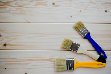 Three different paint brushes on wooden background.  Top view.