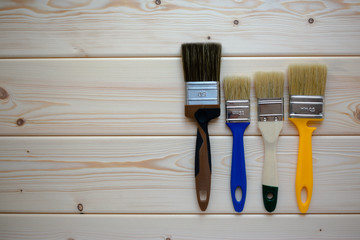 Three paint brushes on wooden background. Top view.  Renovation concept. 