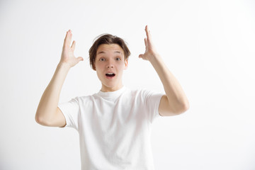 Wow. Attractive male half-length front portrait on gray studio backgroud. Young emotional surprised man standing with open mouth. Human emotions, facial expression concept