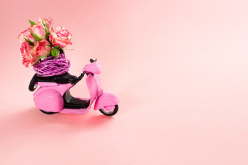 bouquet of roses flower in basket on backseat of cute pink scooter on pink background