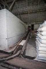 The theme of production and processing. Mechanisms at the old low-tech plant for the production of grain. Factory times of the Soviet Union. Transportation of goods in the enterprise.