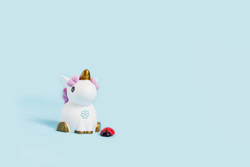 white toy unicorn and ladybug on a blue background
