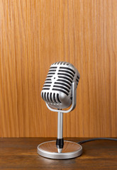 The vintage microphone close up image on wood background.