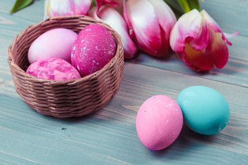 Easter eggs with tulips on blue wooden background