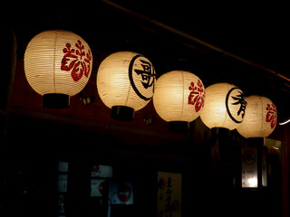 Six traditional Japanese paper lanterns hanging outside a restaurant in Kyoto