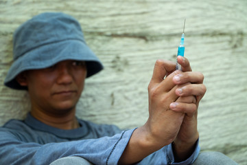 close up of Syringe and Needle in hand of drug addict man. homeless using needle injecting liquid....