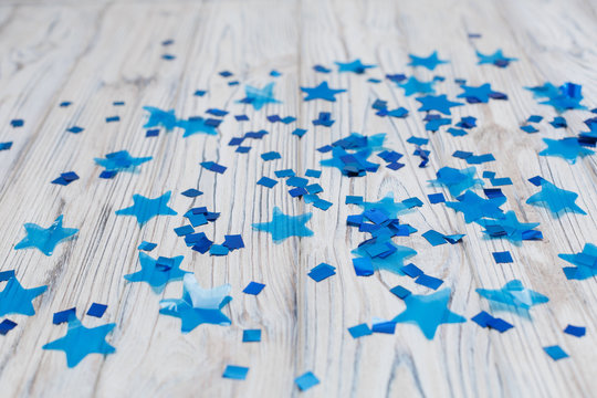 blue shiny stars on a wooden background abstraction. Abstract colorful background with blue elements on a light background. Top view of a train of confetti blue stars on a wooden  background - Powered by Adobe