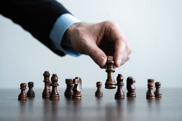 hand of businessman moving chess figure in competition success play. strategy, management or...