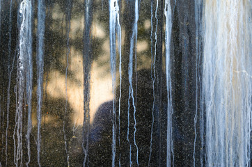 Black Polished Granite Wall with White Outgrowths Leaking from the Weather. Streaks on the Wall
