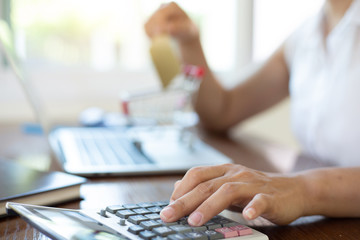 businesswomen using calculator and holding card for shoping online in home office.calculator concept