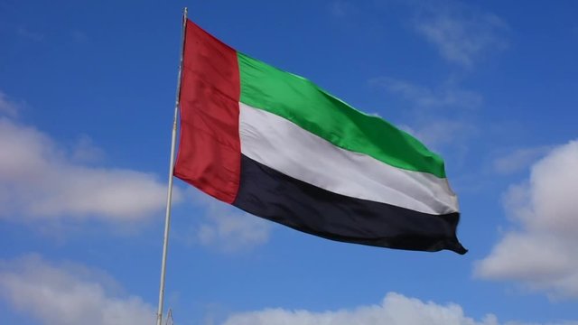 United Arab Emirates Flag flying and waving in the sunshine with a deep blue sky background.