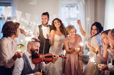 A young bride, groom and other guests dancing and singing on a wedding reception.