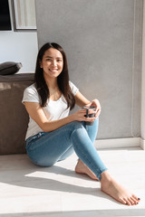 Smiling asian woman holding cup of coffee while