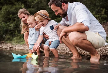 Foto op Aluminium Young family with two toddler children outdoors by the river in summer, playing. © Halfpoint