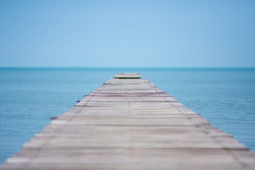 long wooden bridge on the sea with blue sky at sunny day. soft focus.