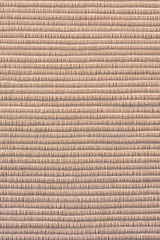 Sofa upholstery close-up. Texture of rough dense ribbed fabric. Light brown blank background for layouts.