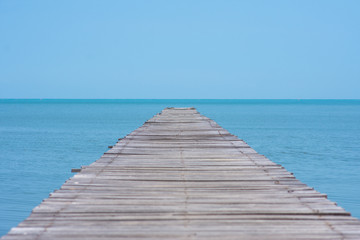 Obraz premium long wooden bridge on the sea with blue sky at sunny day. soft focus.
