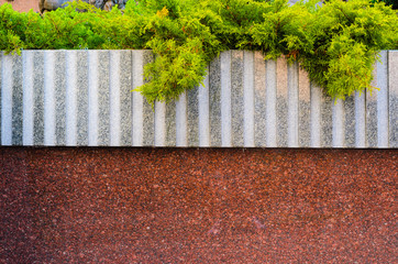 Obraz premium Gray and Red Granite Wall-Bed Becorated with Conifers Plants. Blank Stone Architecture Background