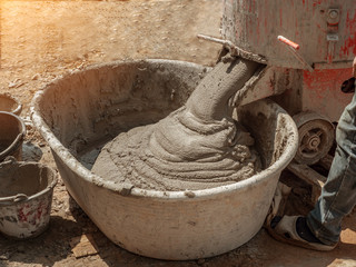 Cement or mortar is inside cement mixer pouring in basin in construction site