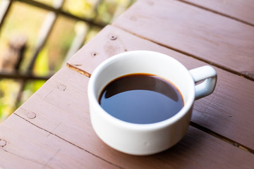 Closeup of white coffee  cup with hot coffee on wood Table.