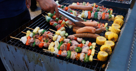 Asian group of friends having outdoor garden barbecue laughing with alcoholic beer drinks on night