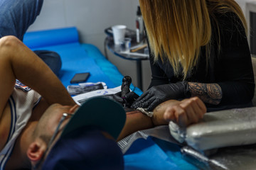 Close up view of the arm of a man who is being tattooed accurately in a studio of a tattooist