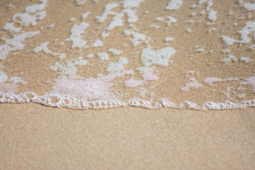 beautiful soft wave on sand at the sea sunny day. subject is blurred.