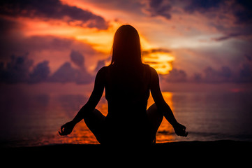 Woman meditating, relaxing in yoga pose at sunset, zen meditation
