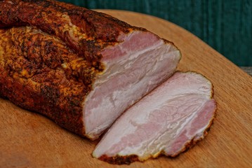 one big piece of smoked bacon lies on a brown wooden board