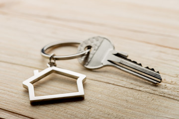 House key with a keychain on wooden desk concept for real estate