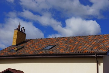 part of a private building with a brown tiled roof and chimney against the sky