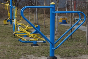 blue yellow metal gym equipment outdoors in the grass