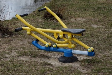 one colored metal sports simulator on the street in the green grass on the lake