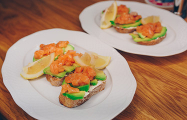 Top view homemade toast sandwich with salmon, avocado, cottage cheese lemon and l microgreen sprouts on dark wooden board background. View from above of healthy food - breakfast in restaurant cafe