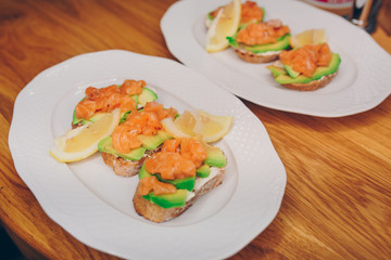 Top view homemade toast sandwich with salmon, avocado, cottage cheese lemon and l microgreen sprouts on dark wooden board background. View from above of healthy food - breakfast in restaurant cafe