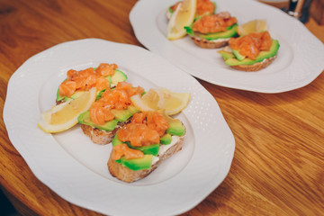 Top view homemade toast sandwich with salmon, avocado, cottage cheese lemon and l microgreen sprouts on dark wooden board background. View from above of healthy food - breakfast in restaurant cafe