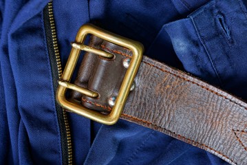 old brown leather belt with brass buckle on blue pants