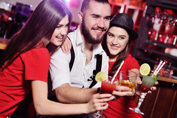 Time Selfie. A group of friends at a party in a nightclub clink glasses with alcoholic beverages. Happy young people with cocktails in the pub.