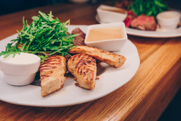 Waiter serving Hot Grilled Skewers chicken beef fillet meat with Fresh arugula Cabbage salad With mustard at restaurant, close up view. Selective focus. Design Gourmet and luxury concept service