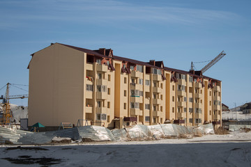 Fototapeta na wymiar Newly built residential building. Ust-Kamenogorsk (Kazakhstan). Modern architecture. New residential area. Construction cranes