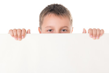 Smiling handsome boy male teenager posing behind white panel on white background. Advertising space for billboard poster