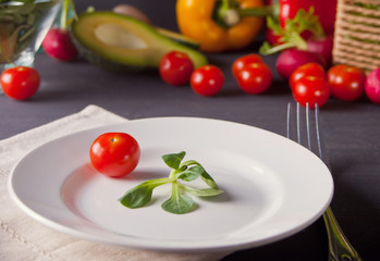 Green fresh leaves with tomato cherry on a white plate. Healthy food.