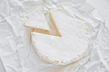 Brie cheese on white paper. White background, top view, close up