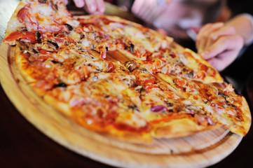 Appetizing hot pizza closeup on a table in the background of a group or company of people friends
