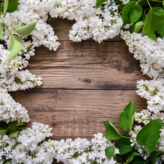 Obraz na płótnie Canvas Frame of white lilac branches on wooden background