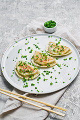 Chinese fried dumplings, chopsticks, fresh green onions. Gray background, top view
