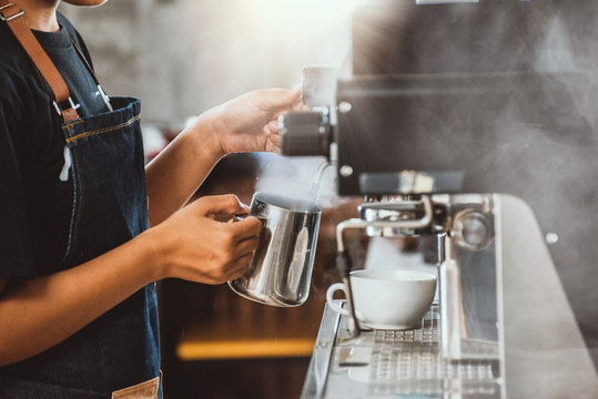 Barista steaming milk in the pitcher with coffee machine, Barista steaming milk in coffeeshop