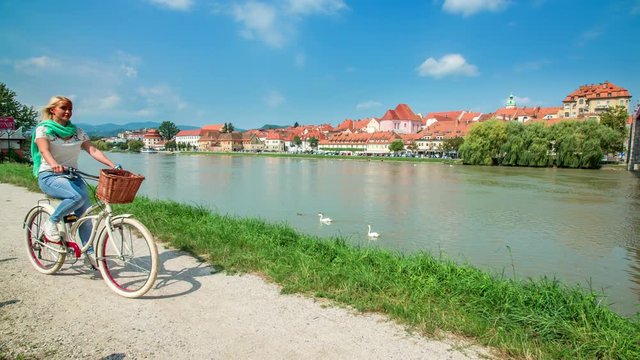 This young woman is enjoying cycling alongside a river in the city of Maribo. It's a summer day and the weather is fantastic.