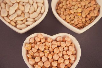 A plates of dry beans, peas and chickpeas on black background.